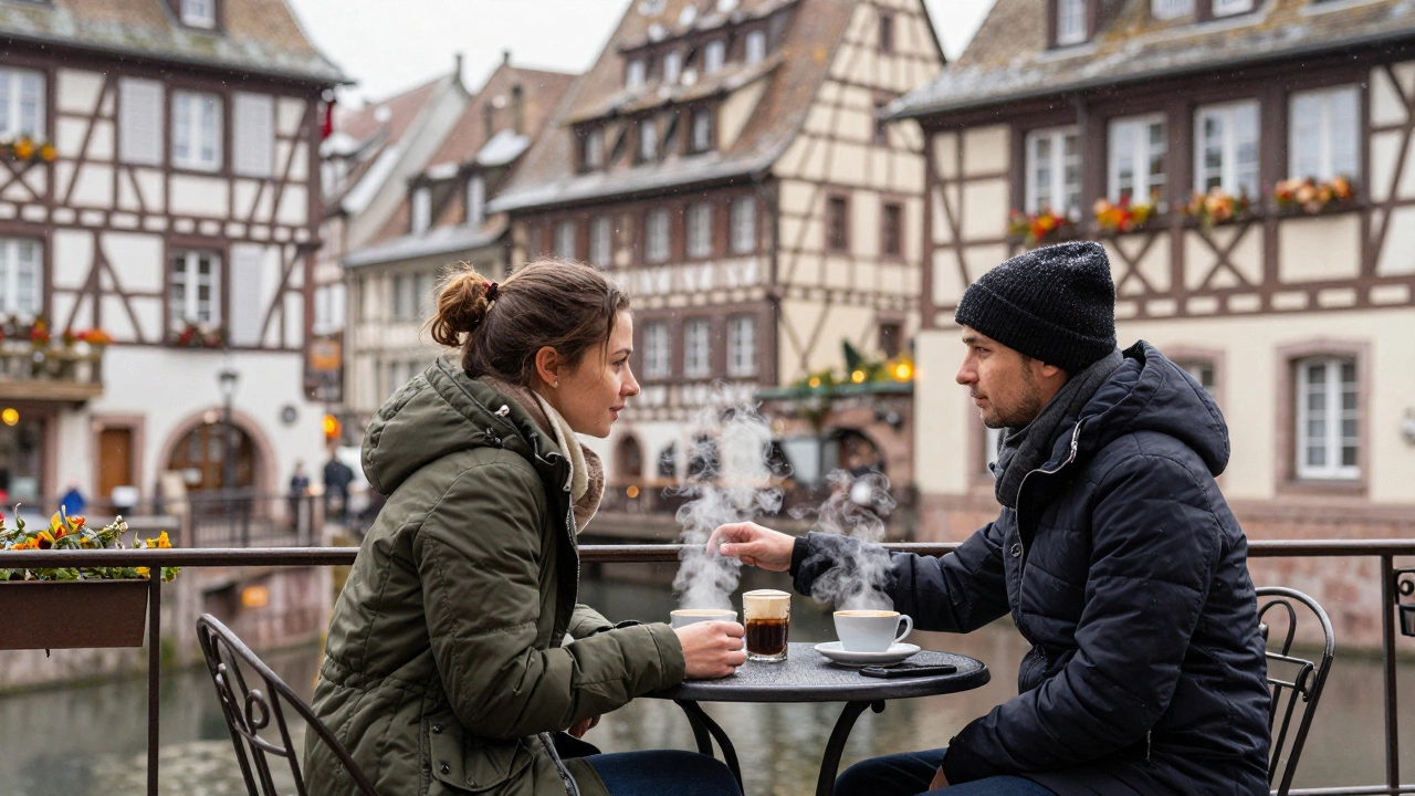 Two people share a quiet moment at a café table in Strasbourg, snow falling as one gently touches the other&#039;s arm.